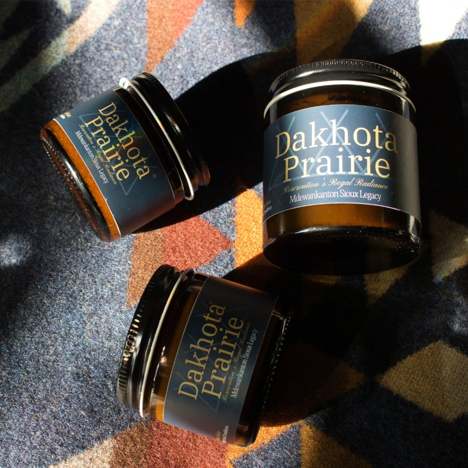 Three Dakhota Prairie product jars lying on tribal blanket