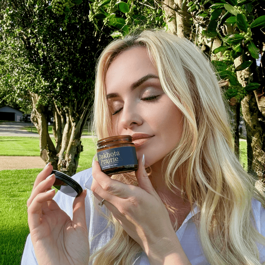 Woman Smelling Dakota Prairie's Salve outdoors with greenery in the background