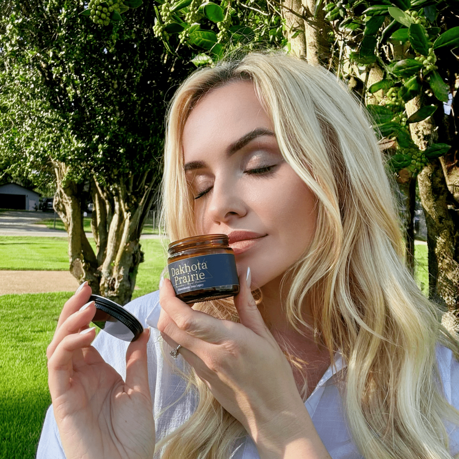 Woman Smelling Dakota Prairie's Salve outdoors with greenery in the background